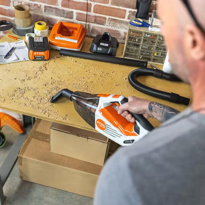 Man Using Vacuum On Work Bench